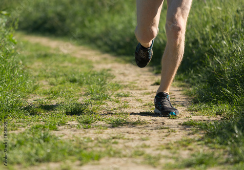 Close up of legs of a man running on a path in the countryside.