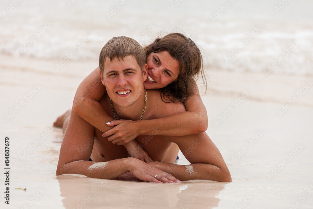 Fototapeta premium Young couple lie on the ocean beach