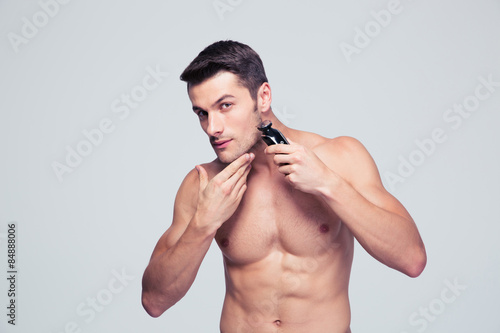 Photography Muscular man shaving with electric razor