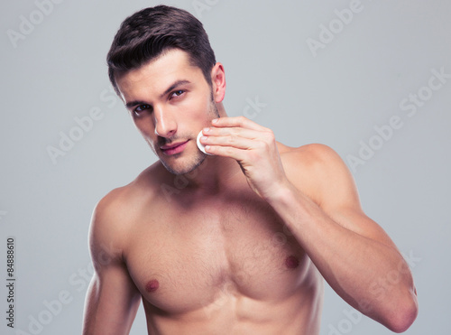 Cuadro en lienzo Man cleaning face skin with batting cotton pads