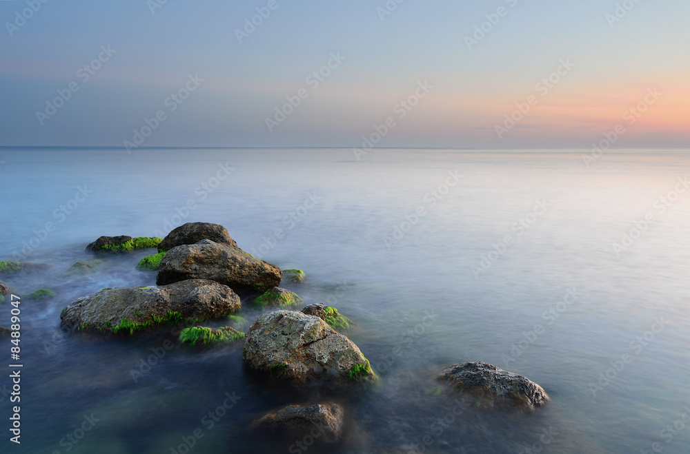 group of stones in a calm sea at sunset