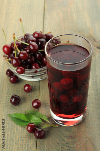Closeup of fresh juice with sweet cherries on a wooden background