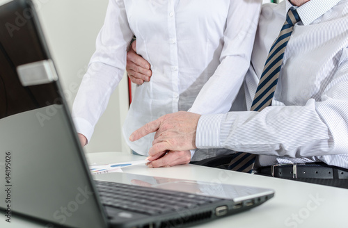 Manager holding his secretary around the waist