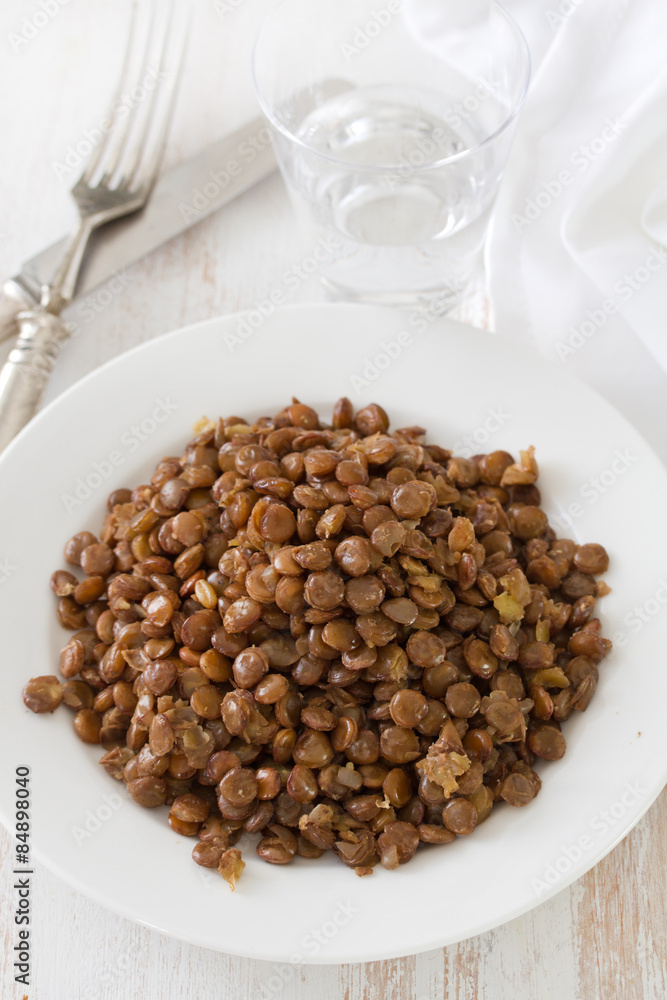 boiled brown lentil on white plate on white wooden background boiled brown lentil on white plate on white wooden background