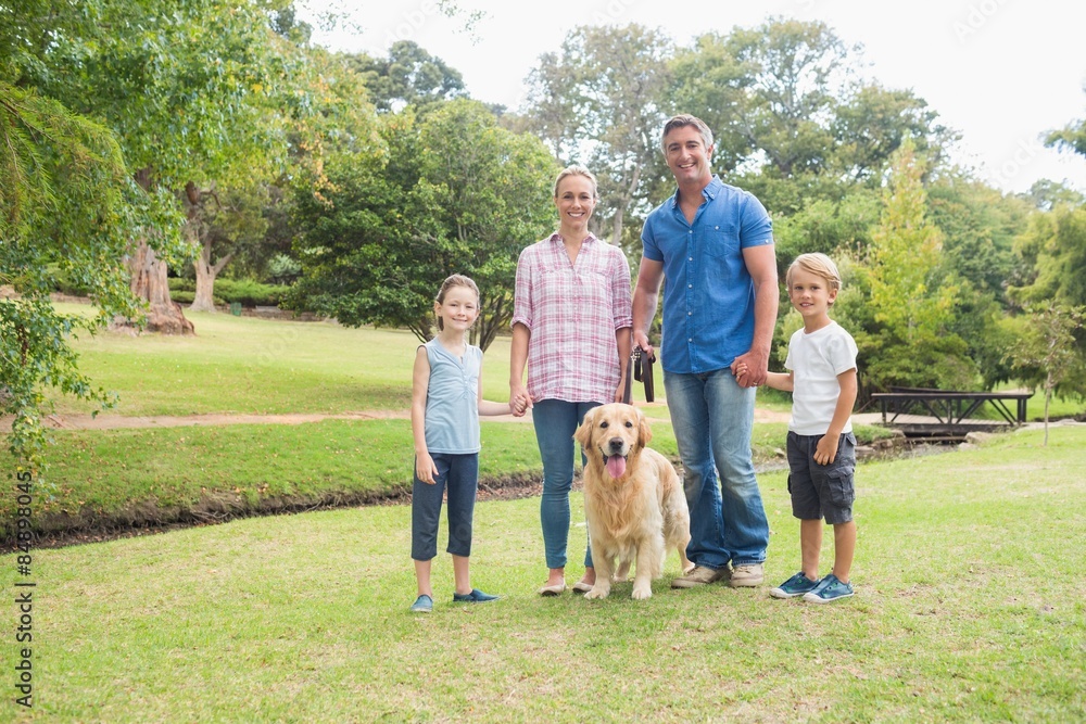 Obraz premium Happy family smiling at the camera with their dog