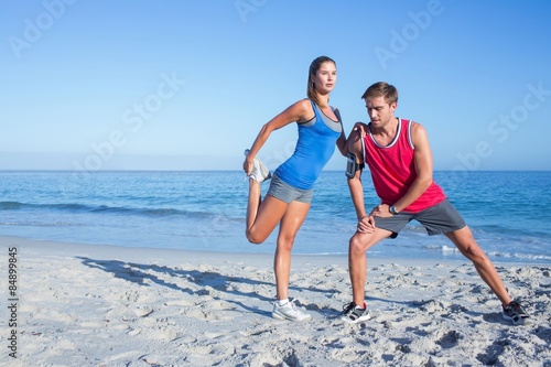 Happy couple stretching together beside the water