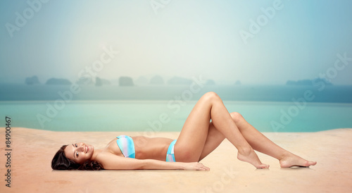 happy woman tanning in bikini over swimming pool