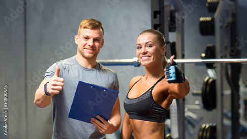 Fotografie smiling young woman with personal trainer in gym
