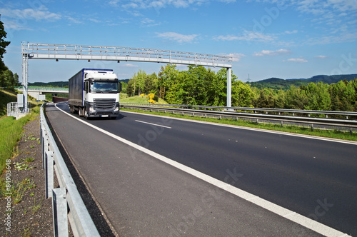 Obraz na płótnie White truck passing through the electronic toll gates on the highway in a wooded landscape w salonie