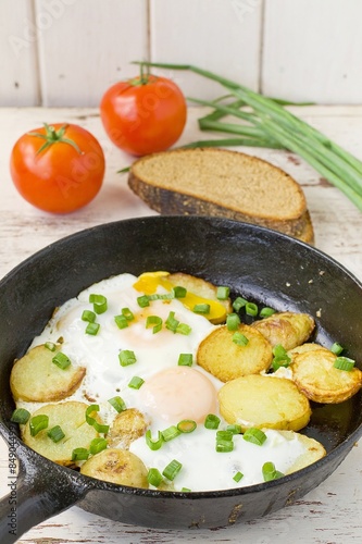 fried potatoes with fried eggs in a frying pan 