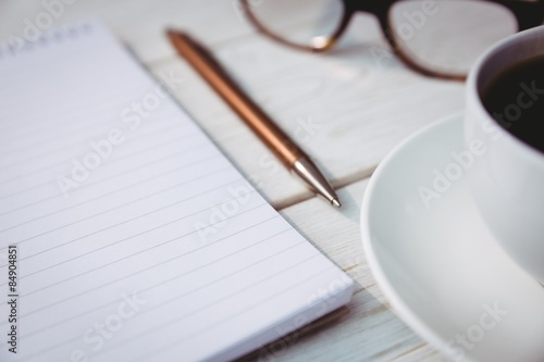Empty notepad with reading glasses and cup of coffee