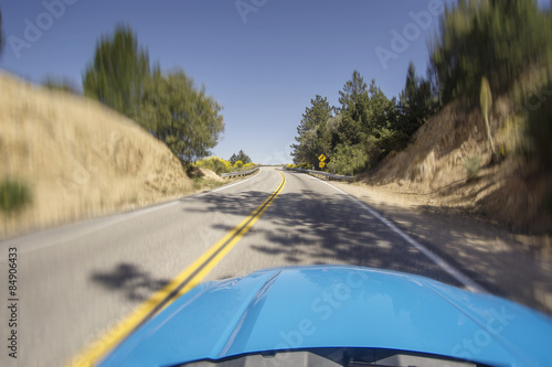 Car driving fast on open mountainous road with bends and turns o