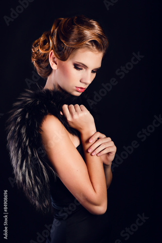 Elegant young woman in black lingerie posing at studio.