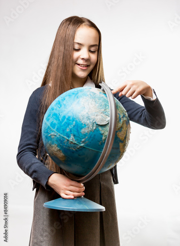 smiling girl in school uniform pointing at Earth globe
