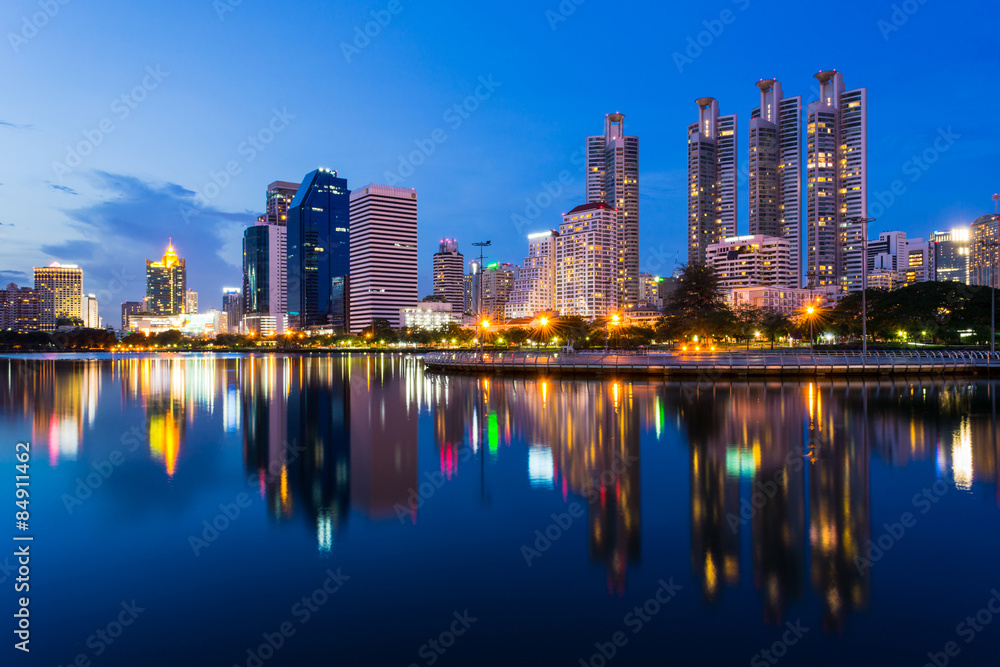 Fototapeta premium Budynki biznesowe w Bangkoku widziane z parku Benjakiti, scena nocna, Tajlandia