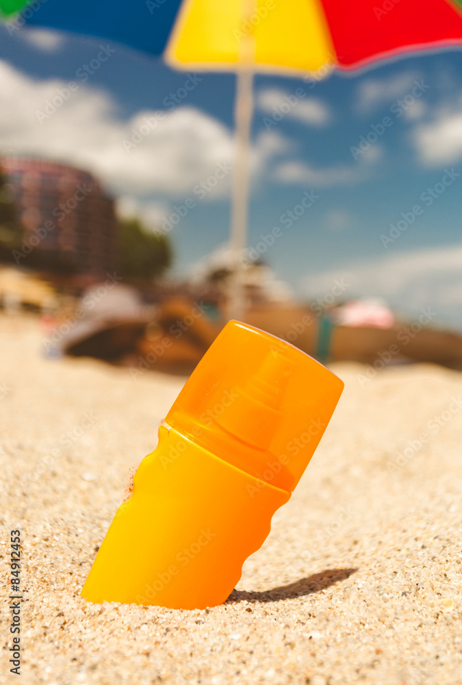 toned photo of suntan lotion on sandy beach at sunny day toned photo of suntan lotion on sandy beach at sunny day