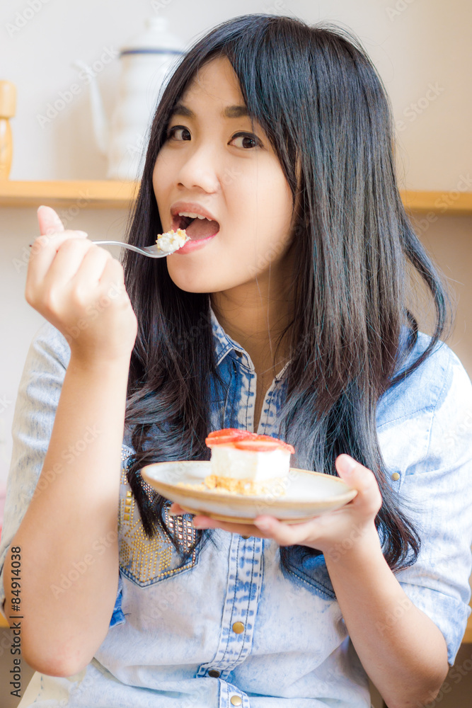 Beautiful smiling young woman biting strawberry cake in bakery s Beautiful smiling young woman biting strawberry cake in bakery s