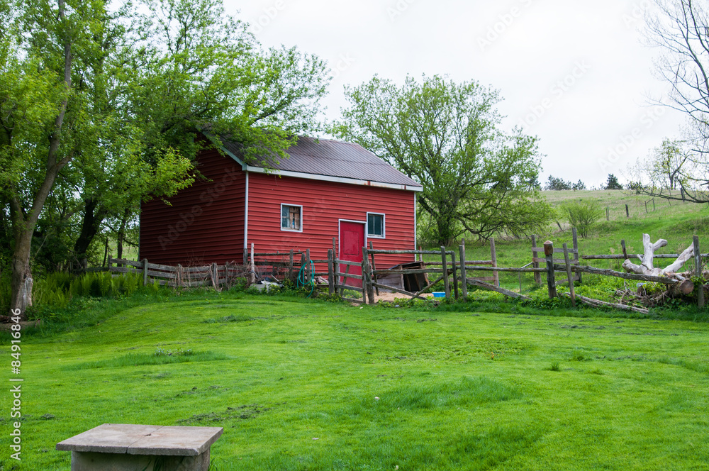 Fototapeta premium old red barn in a green grassy field