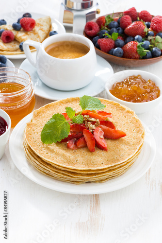crepes with strawberry, jams and honey on white background