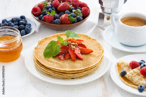 crepes with strawberry, jams and honey on white table