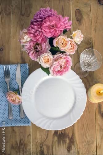 Beautiful festive table setting with roses, candles and napkins 