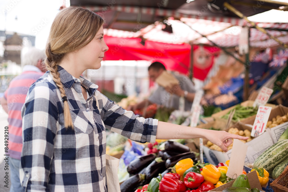 young woman showing a market trader what she wants. young woman showing a market trader what she wants.