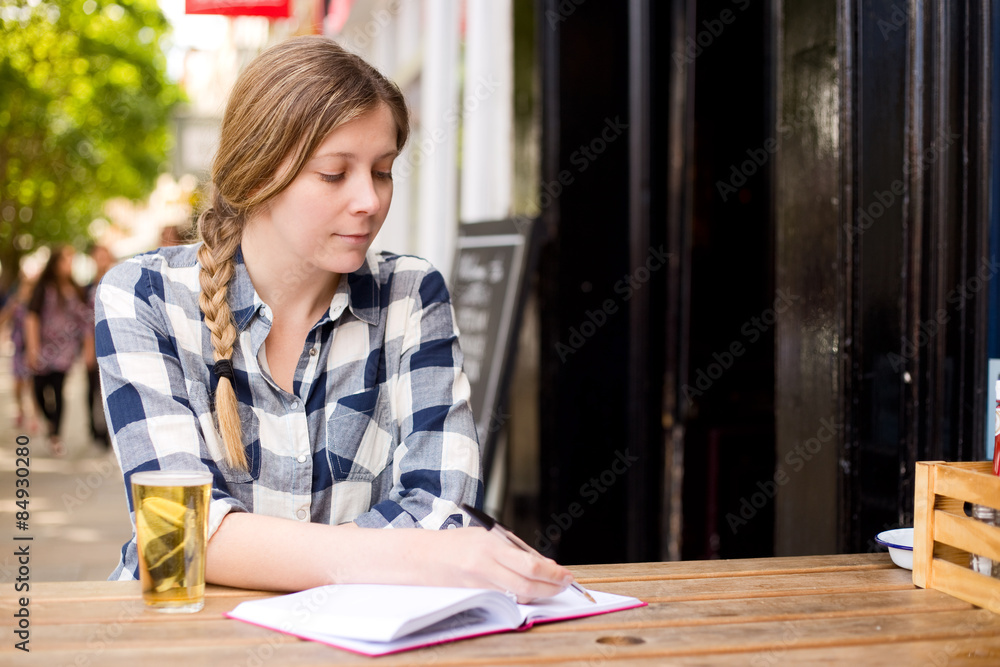 young woman writing in her diary and enjoying a drink. young woman writing in her diary and enjoying a drink.