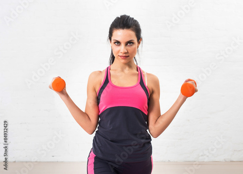 Young woman goes in for sports, fitness with dumbbells. Healthy lifestyle. Health. Shakes hand muscles dumbbells