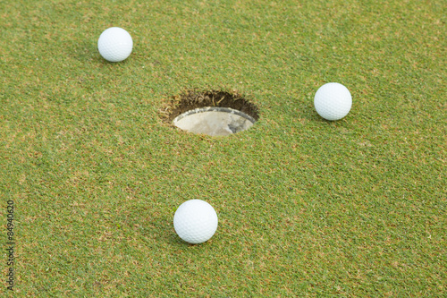 3 white golf beside hole