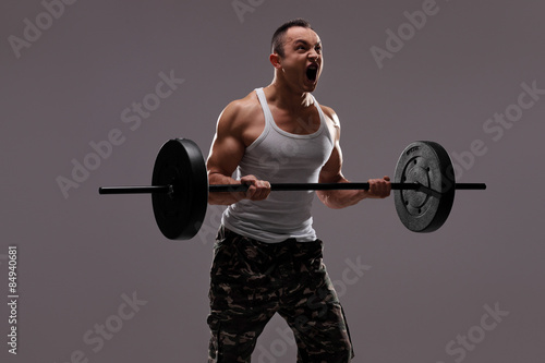 Determined young athlete exercising with a barbell