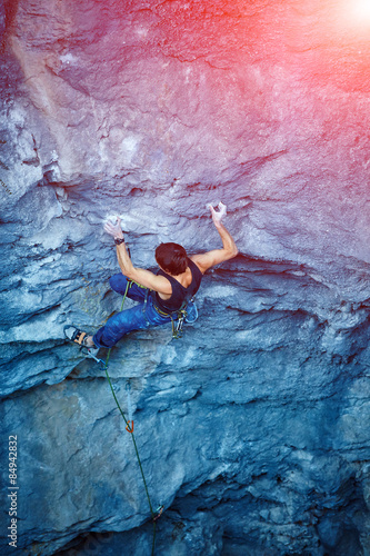 Tableau sur toile Rock climber climbing up a cliff