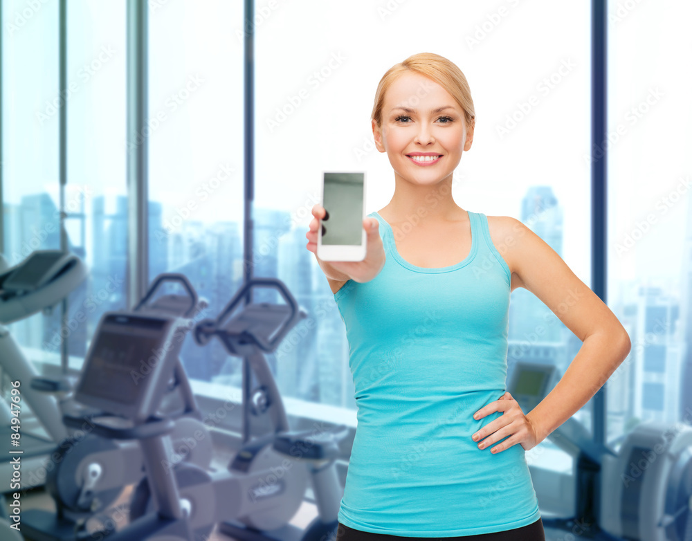 smiling sporty woman showing smartphone in gym smiling sporty woman showing smartphone in gym