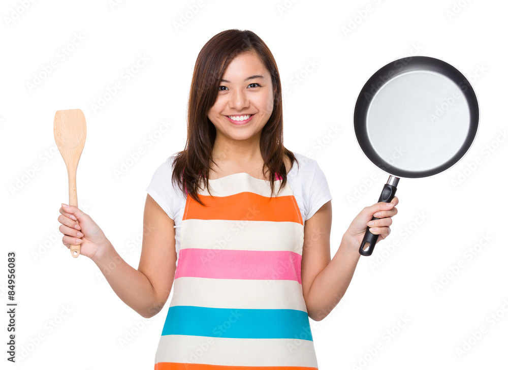 Housewife holding up with frying pan and wooden ladle Housewife holding up with frying pan and wooden ladle