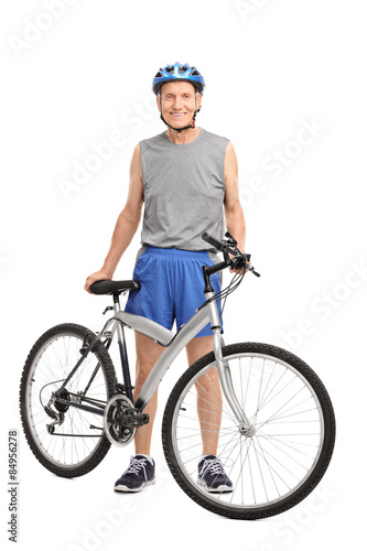 Senior biker standing behind a bicycle and smiling