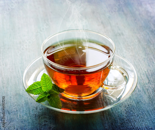 Hot cup of tea with mint leaf on dark rustic background
