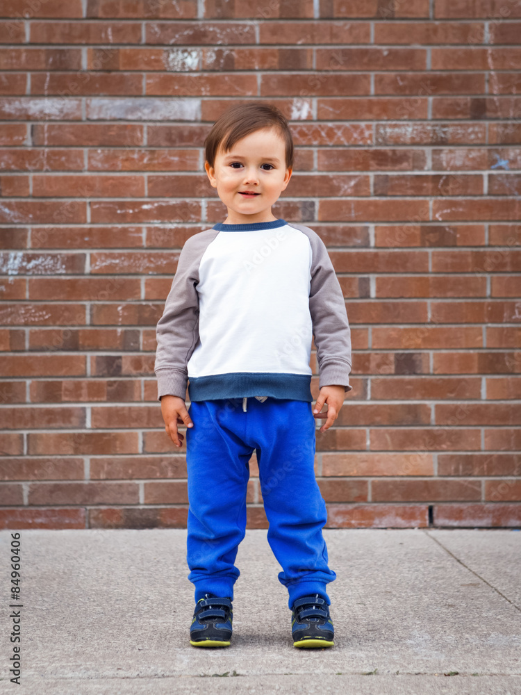 Toddler boy by brick wall laughing Toddler boy by brick wall laughing