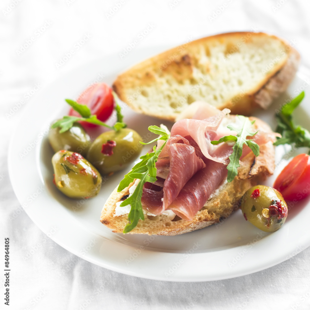 delicious appetizer to wine - toast with ham, olives and cherry tomatoes