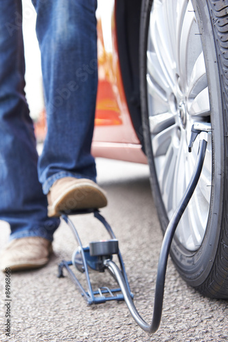 Close Up Of Man Inflating Car Tyre With Foot Pump