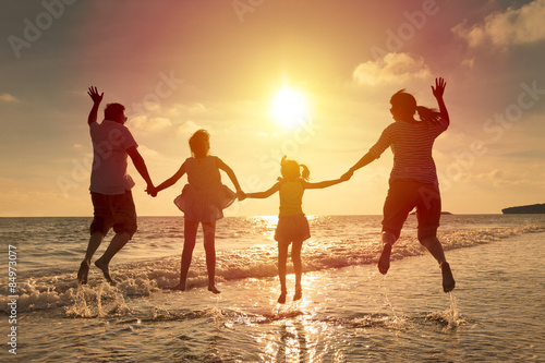 happy family jumping together on the beach