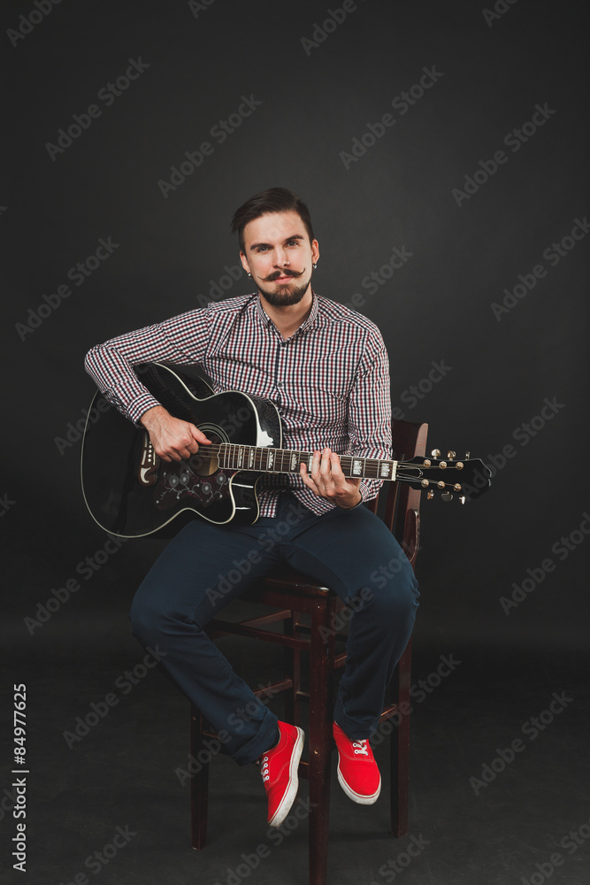 Fototapeta premium handsome guy with beard holding acoustic guitar