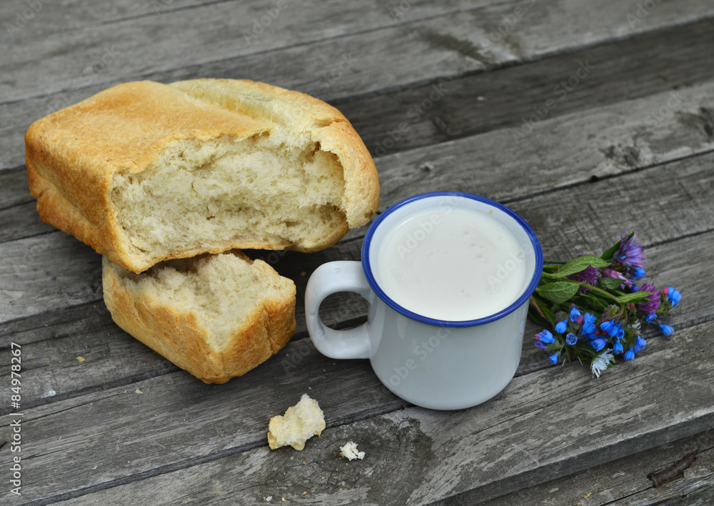 Close up of milk in mug and loaf of bread with flowers Close up of milk in mug and loaf of bread with flowers