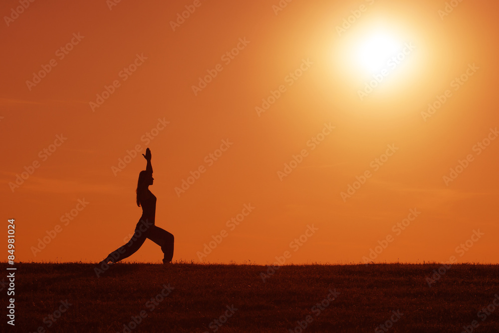 Silhouette of woman meditating in the sunset