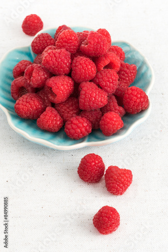 Ripe sweet raspberries on a plate on table close-up