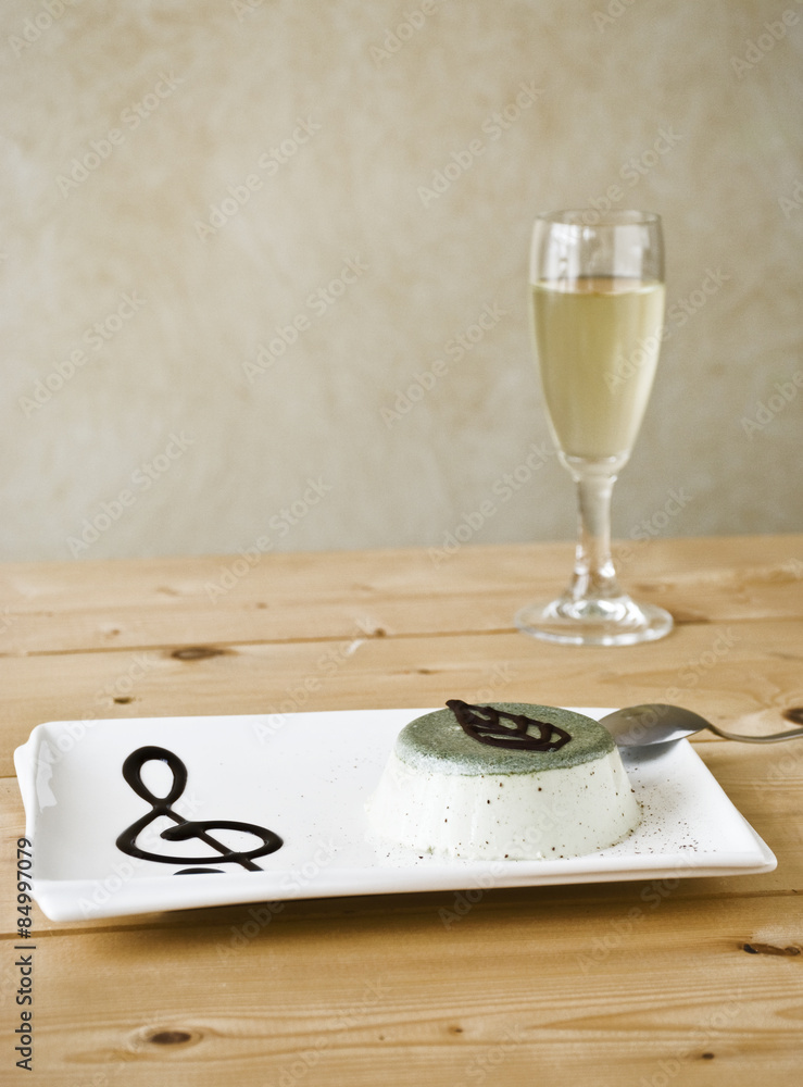 Foto Stock il dolce al cucchiaio,decorato con la chiave di violino e la  foglia di cioccolato,con sullo sfondo il bicchiere di vino bianco | Adobe  Stock