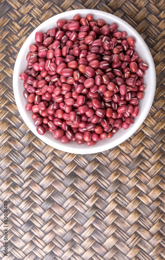 Red adzuki beans in white bowl over wicker background Red adzuki beans in white bowl over wicker background