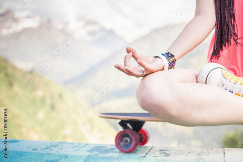 hippie fashion girl doing yoga, relaxing on skateboard at mountain
