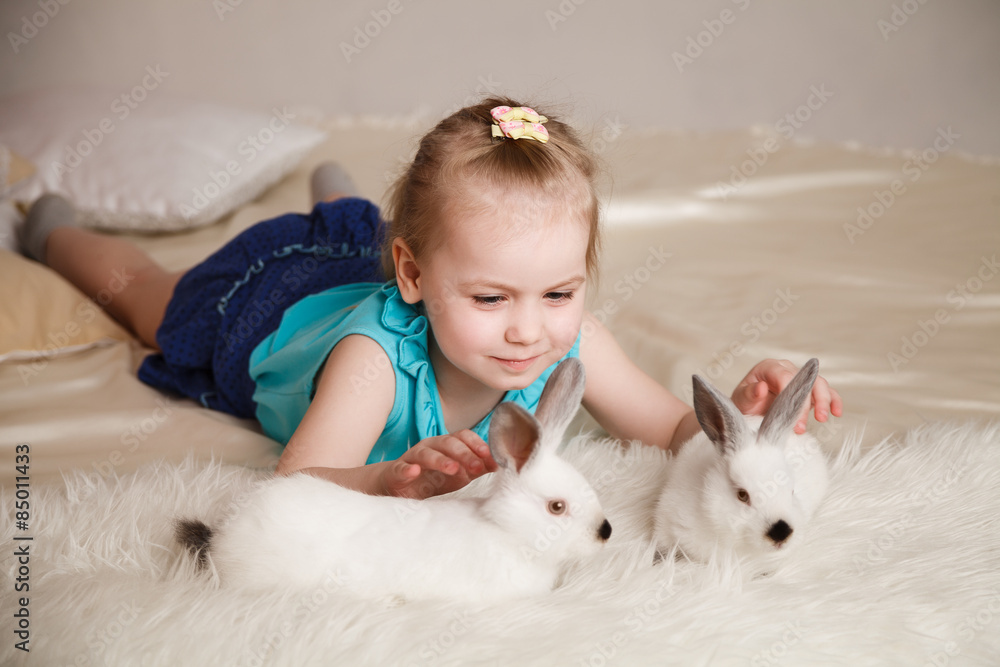 Cute little girl playing with white rabbits Cute little girl playing with white rabbits