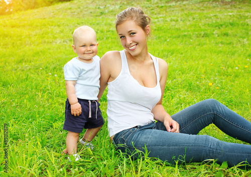 Happy smiling mother and son child sitting on the grass in summe © rohappy