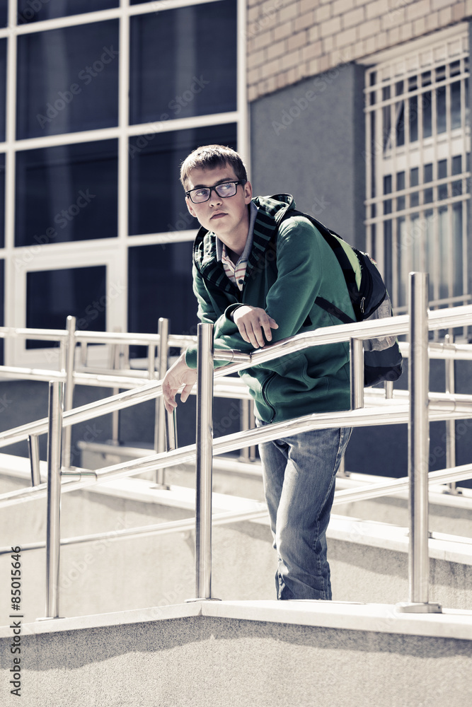 Teen boy with backpack against a school building Teen boy with backpack against a school building