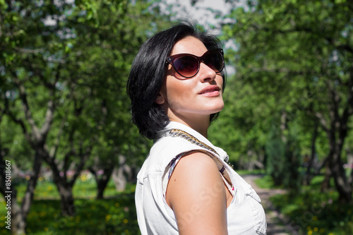 Summer portrait of a beautiful woman in sunglasses at the park